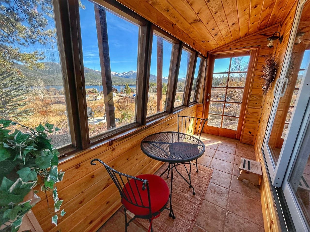 A wooden cabin with large windows offering a view of a mountainous landscape.