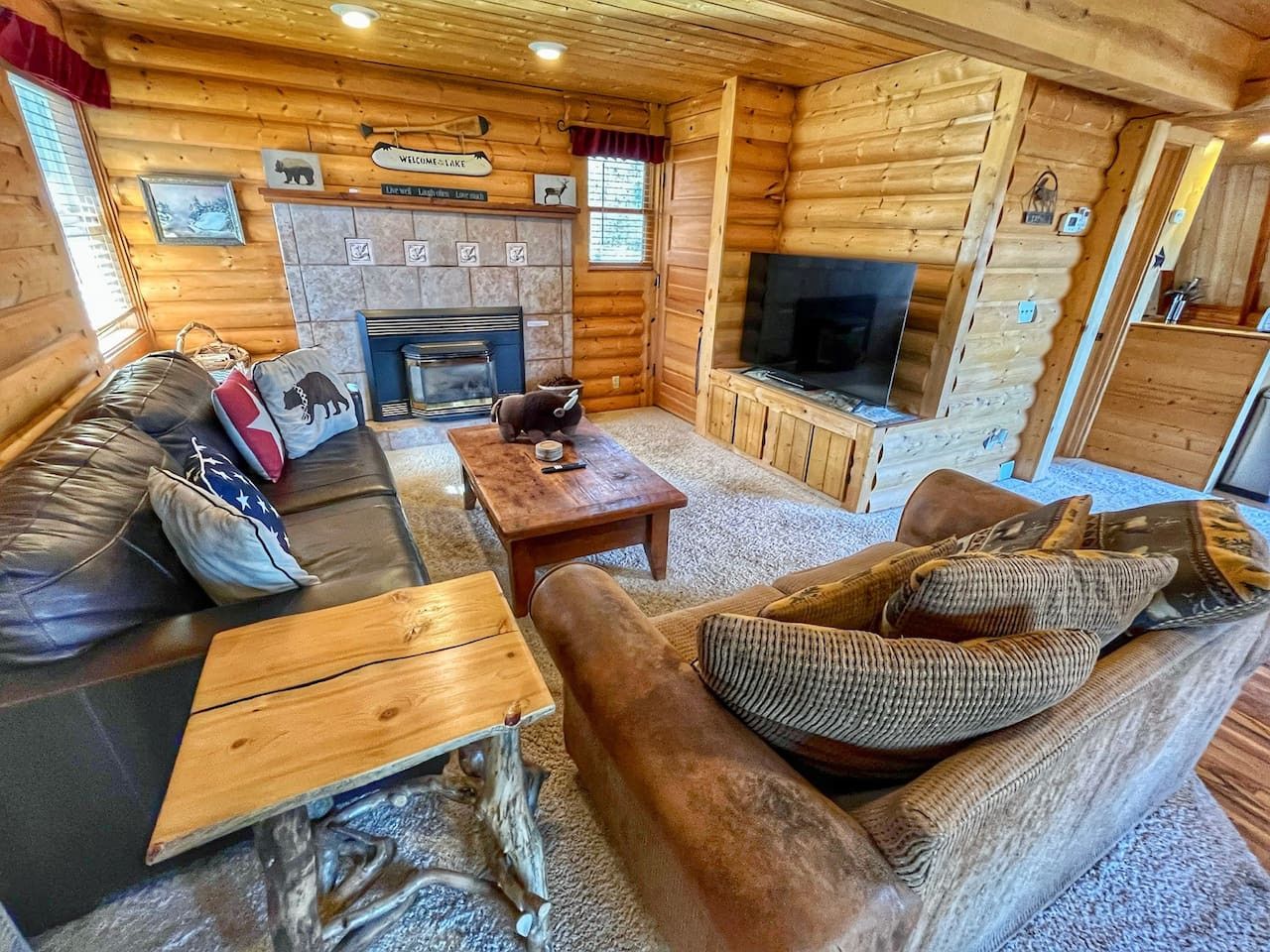 L’intérieur d’un chalet confortable, avec une cheminée, des meubles en bois et un téléviseur.