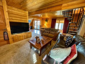A cozy cabin interior with a wooden interior, a fireplace, a television, and a staircase. - Relax in the night sky w/ hot tub (Grand Lake)