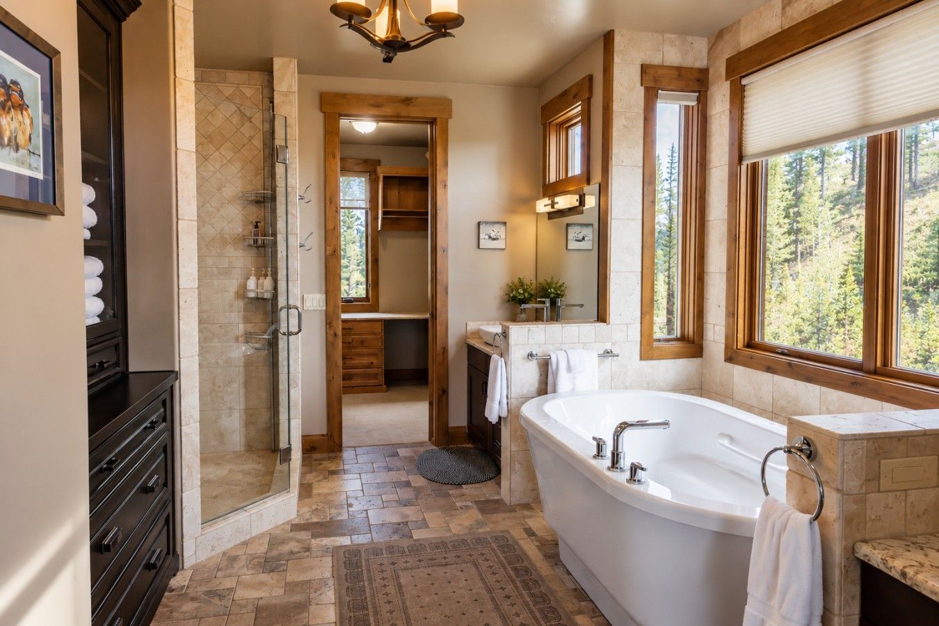 A modern bathroom with a freestanding bathtub, a walk-in shower, and a large window offering a forest view.