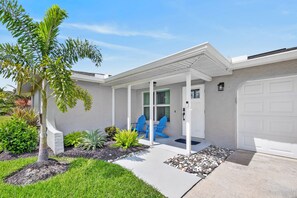 Ein Wohnhaus mit überdachter Veranda, Garage und gepflegtem Garten.