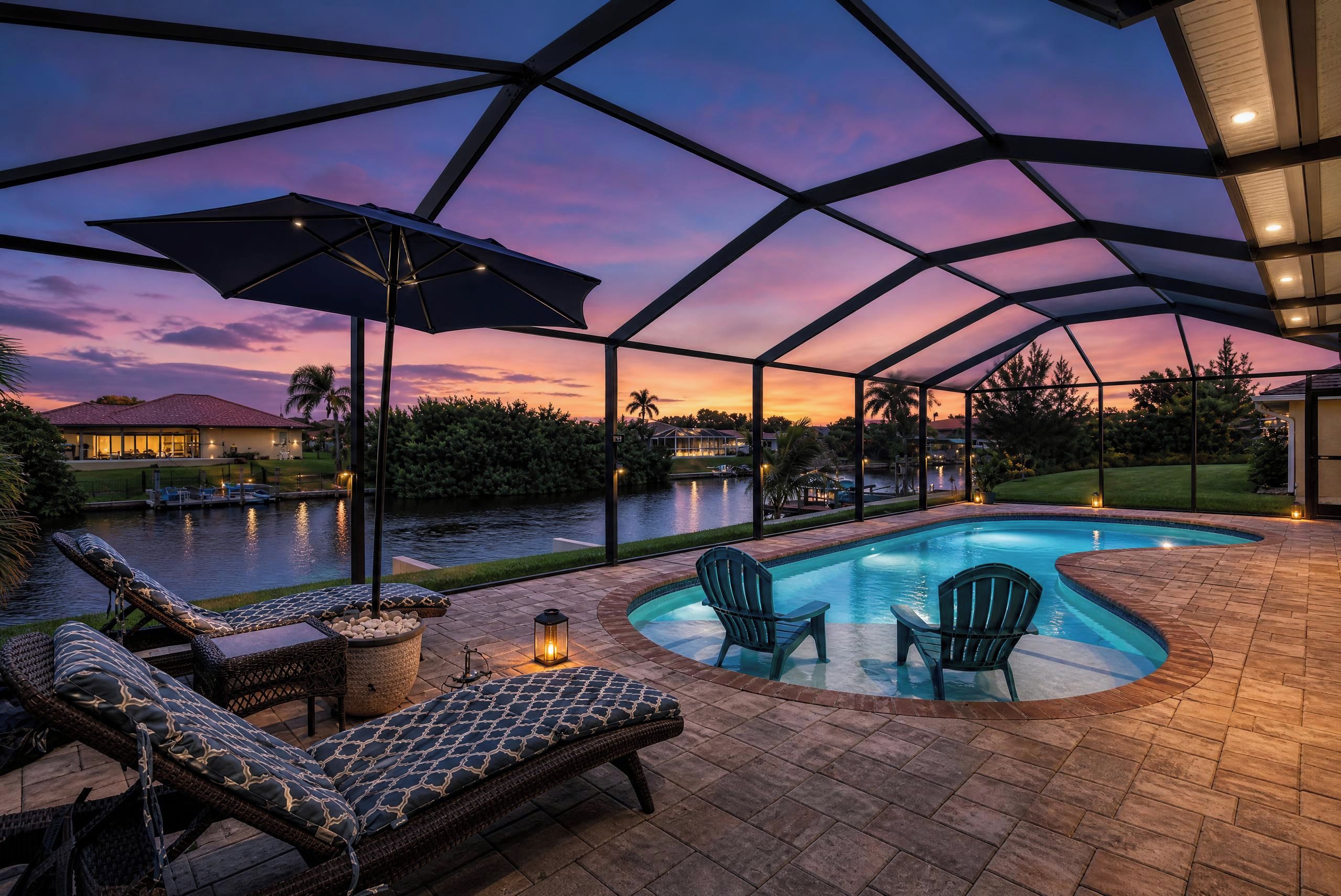 A covered outdoor swimming pool area with lounge chairs and a view of a body of water.
