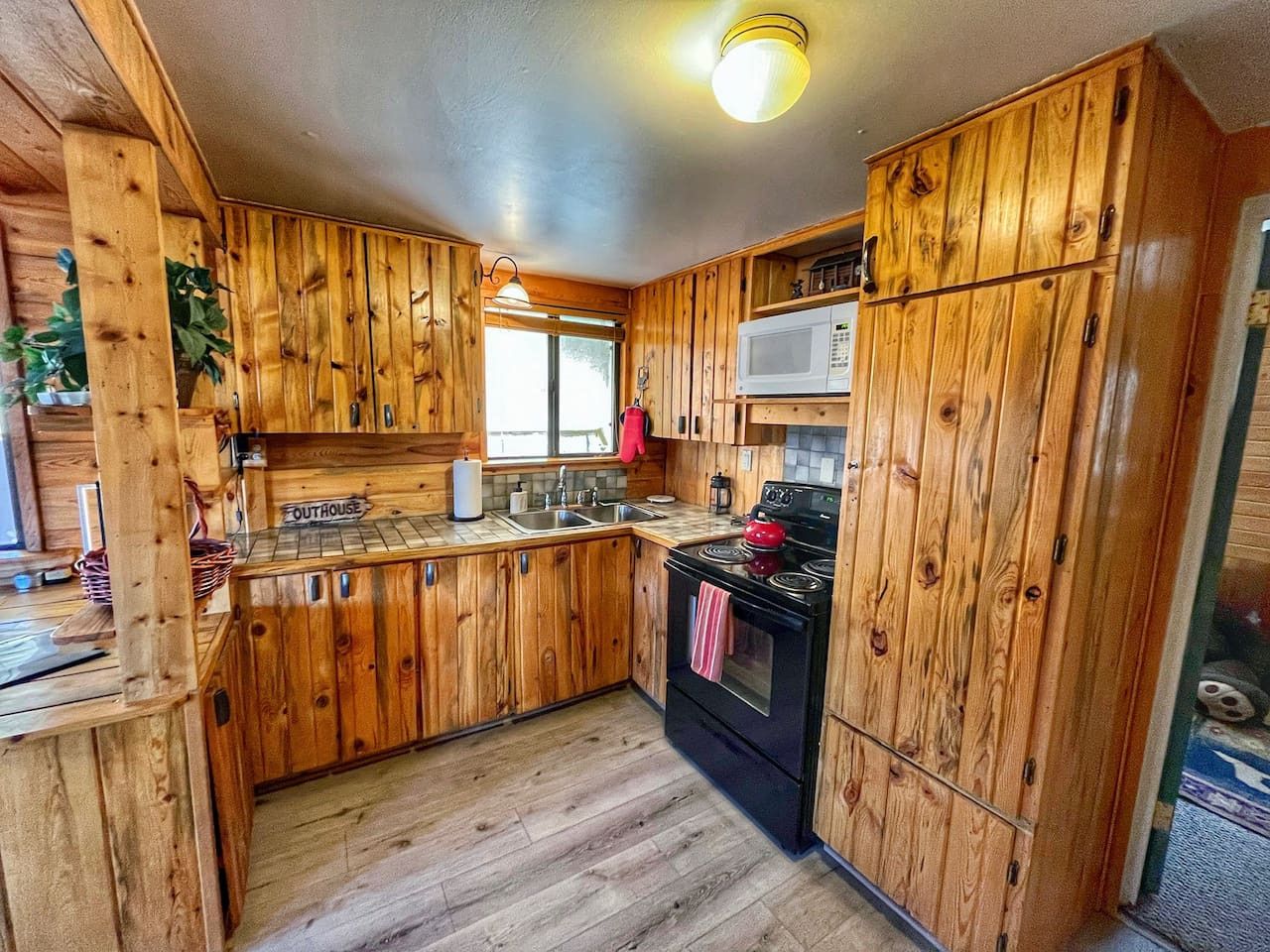 Una cocina con armarios de madera, estufa, microondas y pileta.