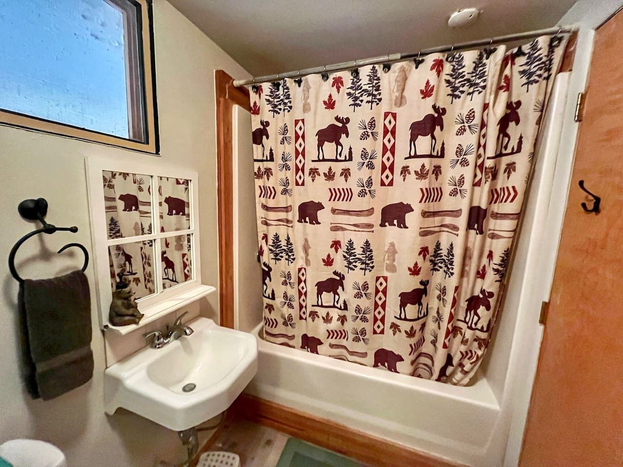 A bathroom with a white sink, a mirror, and a shower curtain with a nature pattern.