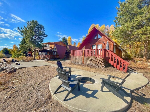 A cabin with a deck, a fire pit, and outdoor seating.