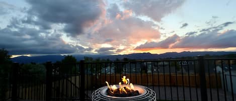 A deck with a metal fire pit in the center, surrounded by a wooden deck and a metal railing.