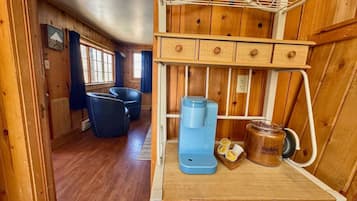 A wooden cabin interior with a bunk bed, a coffee maker, and a jar of honey.