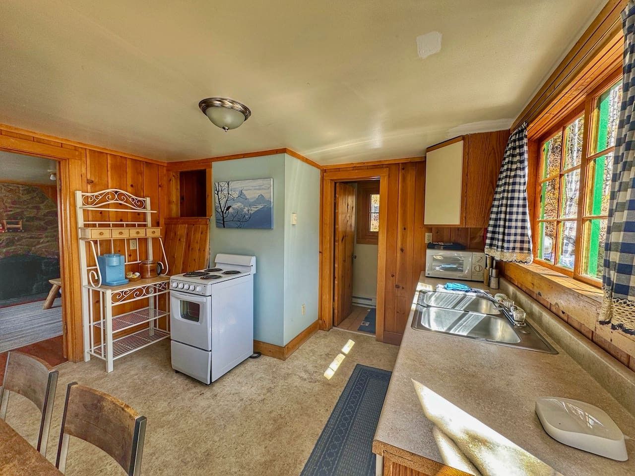 A compact kitchen with a stove, sink, and wooden cabinets.