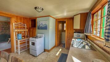 A compact kitchen with a stove, sink, and wooden cabinets.