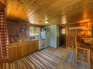 Eine gemütliche Küchenzeile im Blockhausstil mit Holzschränken, einem Herd und einem Kühlschrank.