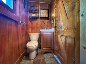 Une salle de bain en bois avec des toilettes, un lavabo et un meuble.