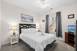 A bedroom with a bed, two bedside lamps, a ceiling fan, a window with curtains, and a television on a wooden stand. - Magnolia Pointe Golf & Beach Retreat Myrtle Beach (Myrtle Beach)