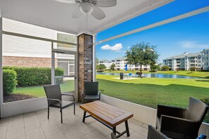 A balcony with a table and chairs, a ceiling fan, and a view of a residential area with a pond and buildings. - Magnolia Pointe Golf & Beach Retreat Myrtle Beach (Myrtle Beach)