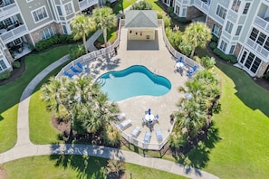 An aerial view of a residential complex with a central swimming pool surrounded by lounge chairs and palm trees. - Magnolia Pointe Golf & Beach Retreat Myrtle Beach (Myrtle Beach)