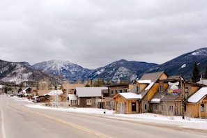A small town with wooden buildings, a road, and snow-covered mountains in the background. - Walk to town, natural lake and MTN view, balcony (Grand Lake)