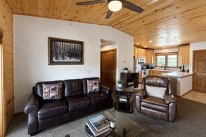 A cozy living room with a leather sofa and armchair, a coffee table with books, and a painting on the wall. - Walk to town, natural lake and MTN view, balcony (Grand Lake)