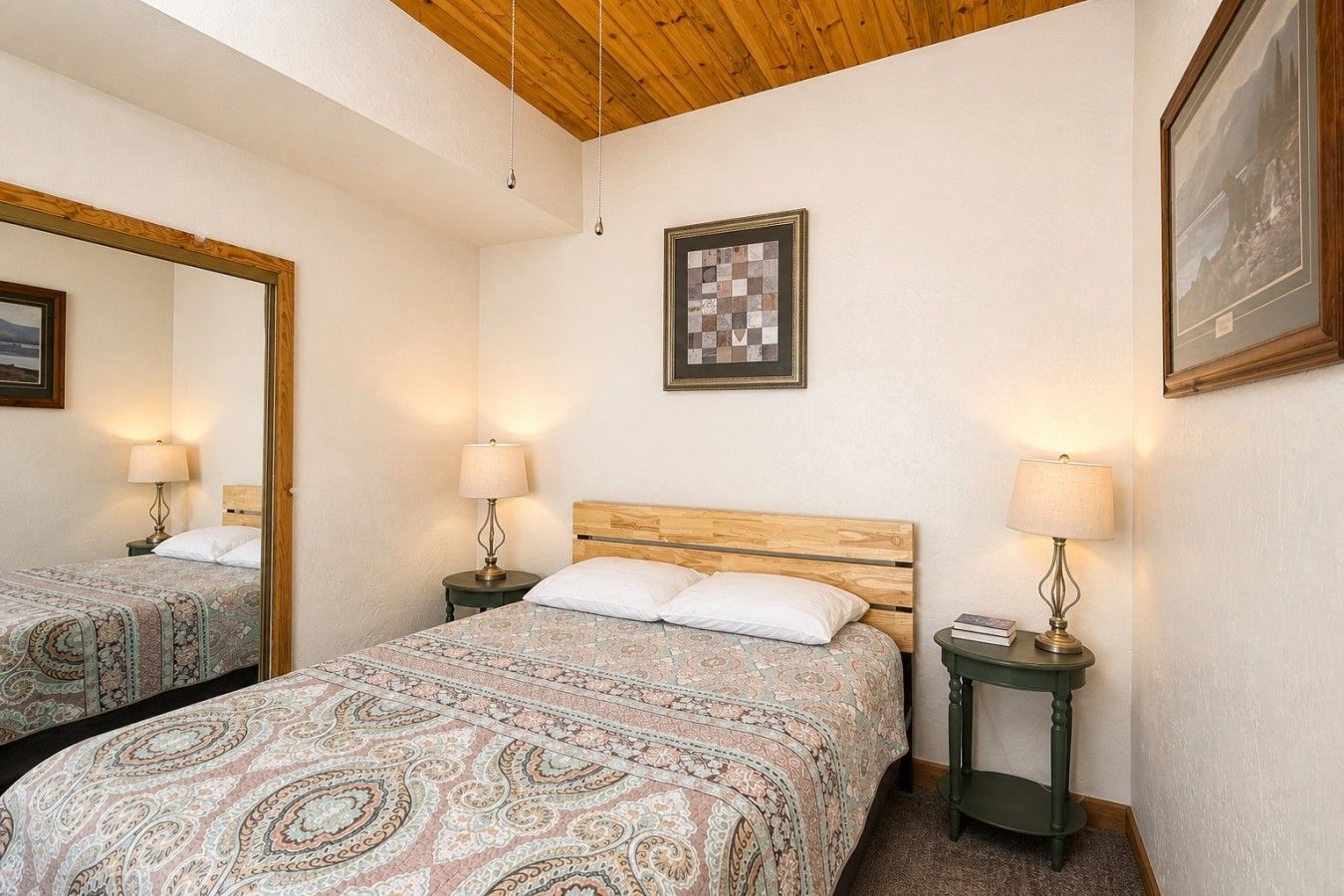 A bedroom with two beds, a wooden ceiling, a framed artwork, and bedside lamps.