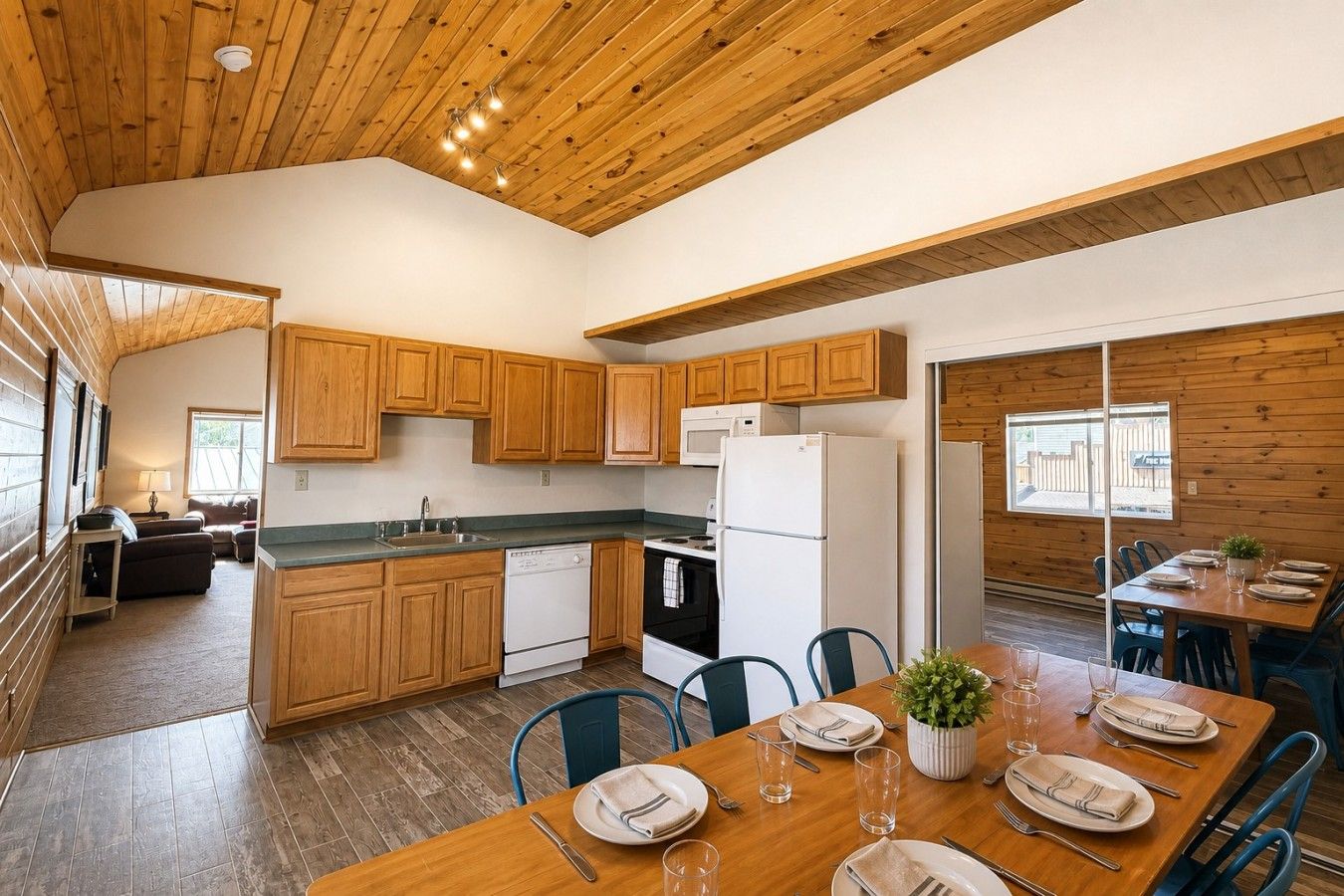 A modern kitchen with wooden cabinets, a dining table set for four, and a view of the outdoors.