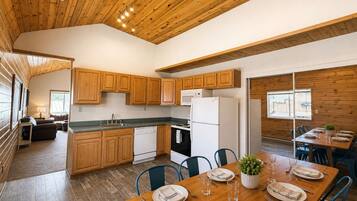 A modern kitchen with wooden cabinets, a dining table set for four, and a view of the outdoors.