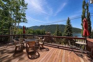 A wooden deck with outdoor furniture and a view of a lake and mountains. - Grand Lake town view Apartment with King size bed (Grand Lake)