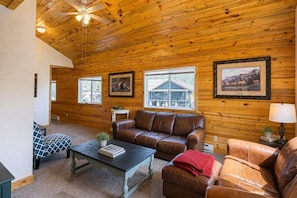 A cozy cabin interior with a wooden ceiling, leather sofas, a coffee table, and framed pictures on the walls. - Grand Lake town view Apartment with King size bed (Grand Lake)