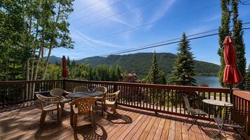 A wooden deck with outdoor furniture and a view of a lake and mountains.