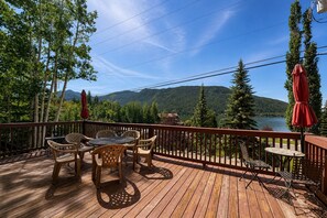 A wooden deck with outdoor furniture and a view of a lake and mountains. - Studio apartment, heart of Grand Lake, Lake views (Grand Lake)