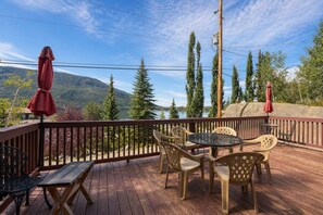 A deck with outdoor furniture, a view of a lake, and a forested mountain backdrop. - Studio apartment, heart of Grand Lake, Lake views (Grand Lake)