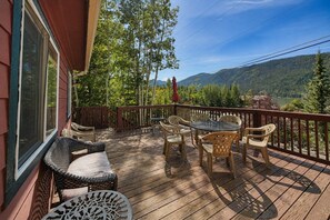 A wooden deck with outdoor furniture, a view of a forested mountain range, and a lake. - Studio apartment, heart of Grand Lake, Lake views (Grand Lake)