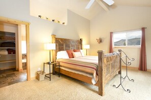A bedroom with a wooden bed, bedside lamps, a window with a view, and a built-in wardrobe.