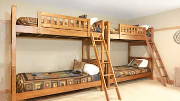 A bunk bed room with a ladder, wooden headboard, and patterned bedding.