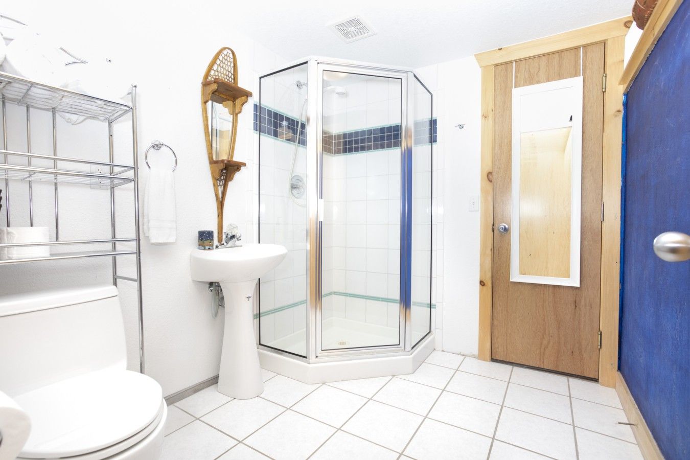 Une salle de bain comprenant des toilettes, un lavabo, une douche en verre et une porte en bois.