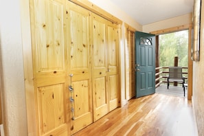 A wooden hallway with a door leading to a balcony with outdoor seating. - Glacial boulder cabin with panoramic mountain view (Grand Lake)