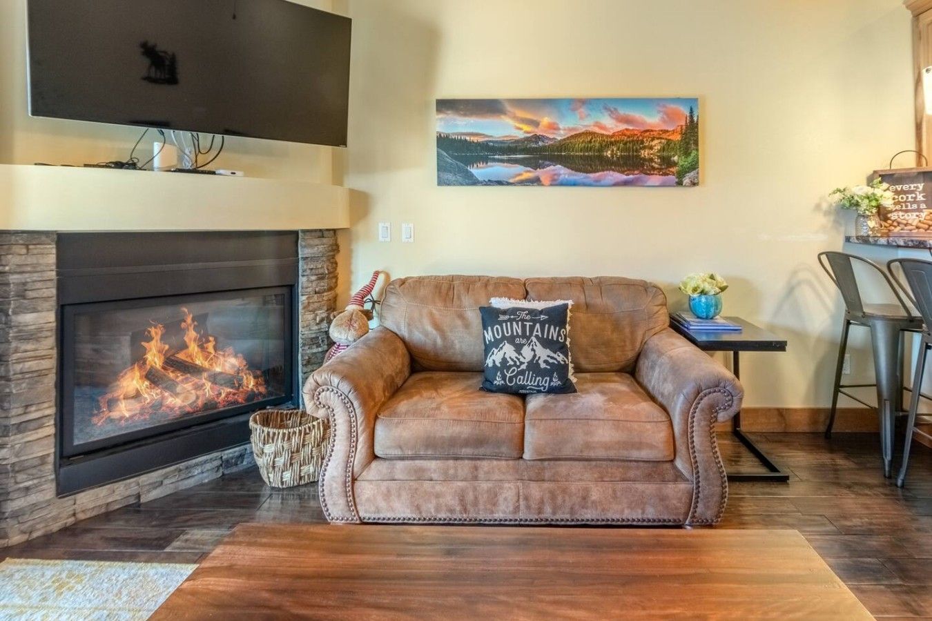 Una sala de estar acogedora con chimenea, un sofá de cuero, un cuadro y un comedor.