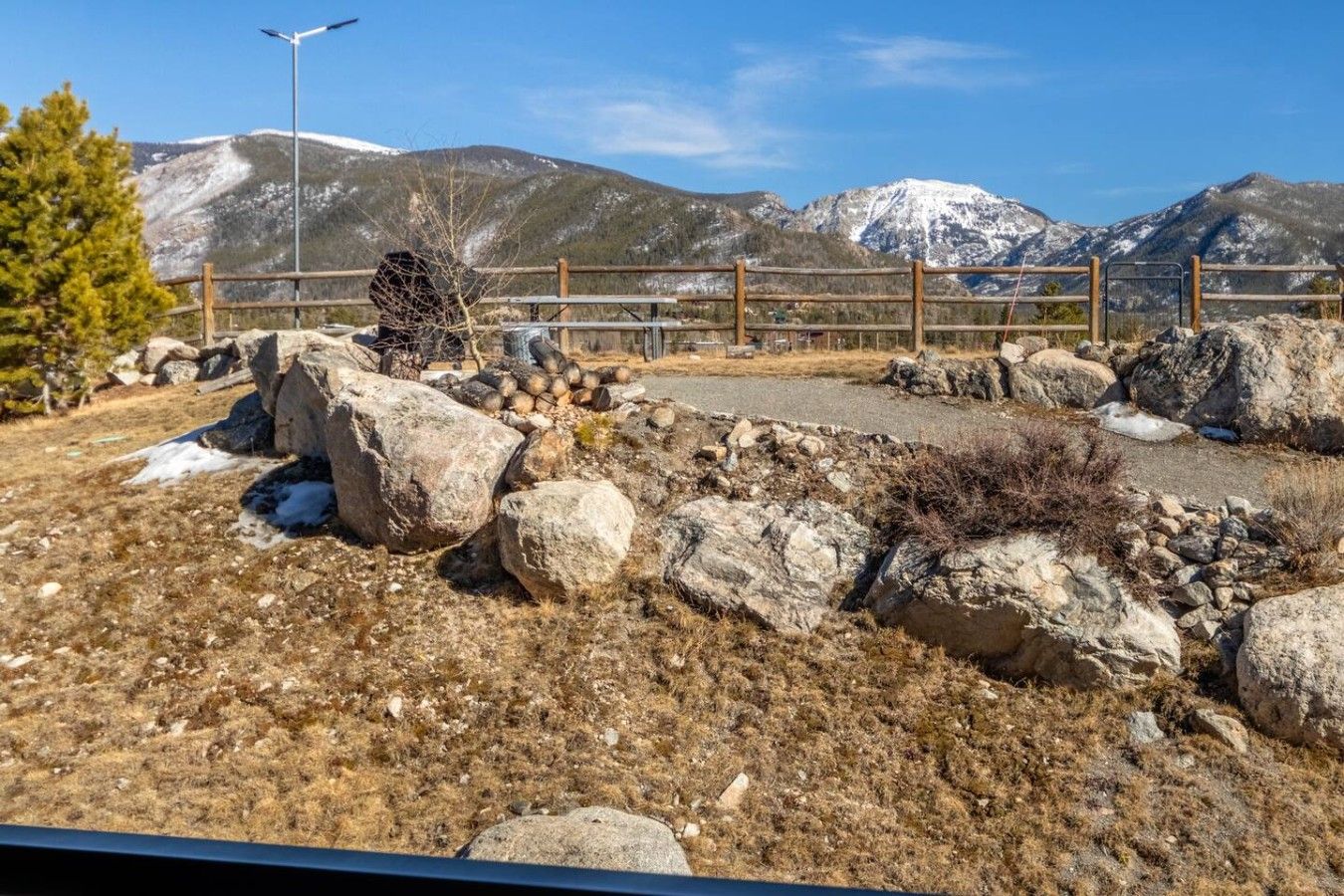 A mountainous landscape with a fenced area containing rocks and sparse vegetation.