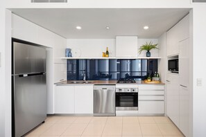 Een moderne keuken met witte kasten, roestvrijstalen apparatuur en een vaatwasser.