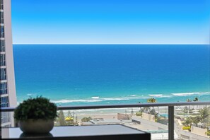 A balcony with a view of the ocean, a potted plant, and a building in the background. - Circle on Cavill Ocean View (Surfers Paradise)