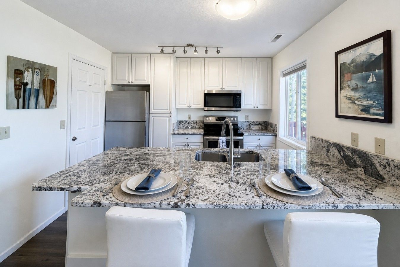 A modern kitchen with white cabinets, a granite countertop, and a central island with seating.