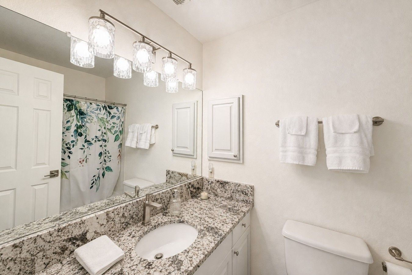 A bathroom with a marble sink, a toilet, and a shower curtain with a floral pattern.