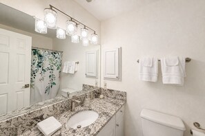 A bathroom with a marble sink, a toilet, and a shower curtain with a floral pattern. - Luxury downtown Apartment with Grand Lake views (Grand Lake)