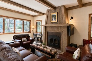 A cozy living room with a fireplace, leather sofas, and large windows. - Lakeside luxury mountain getaway (Grand Lake)