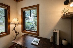 A room with a wooden desk, a lamp, books, and a window with a view of greenery. - Lakeside luxury mountain getaway (Grand Lake)