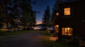 Eine Hütte mit Seeblick in der Abenddämmerung, umgeben von Bäumen.