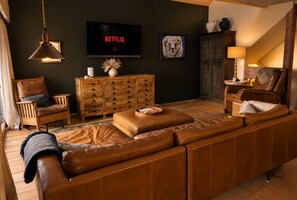 Een woonkamer met een bruine leren bank, een houten kast en een televisie waarop 'NETFLIX' staat.