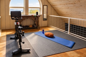 Een kamer met een loopband, een yogamat en een massageapparaat.