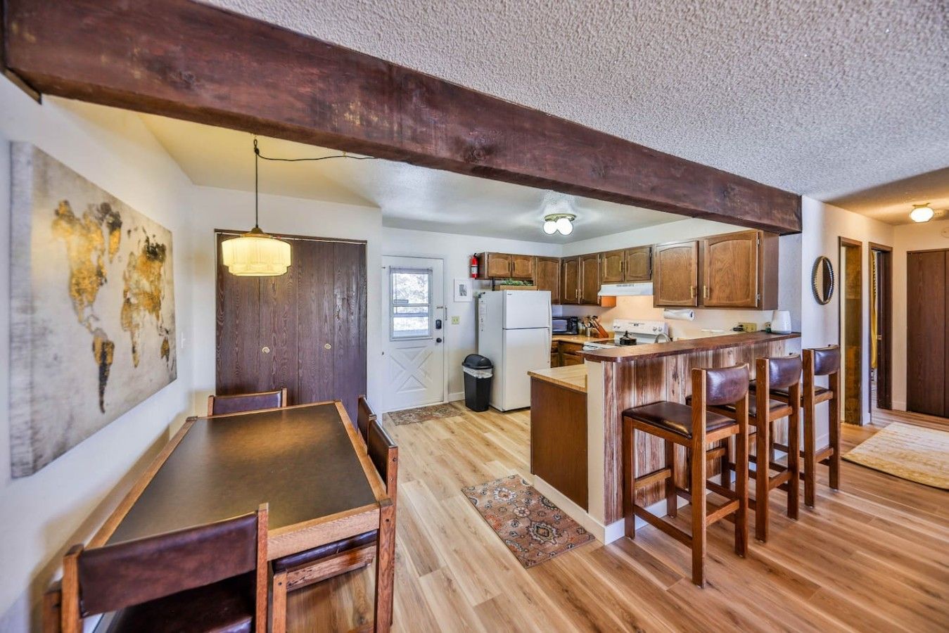 A kitchen with wooden cabinets, a central island, and a dining area with a table and chairs.