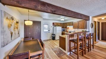A kitchen with wooden cabinets, a central island, and a dining area with a table and chairs.