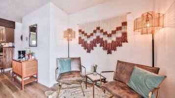 A cozy living area with a sofa, two armchairs, a coffee table, and a wall-mounted lamp.