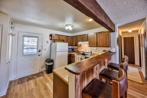 A compact kitchen with wooden cabinets, a built-in bar area, and a refrigerator.