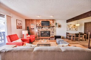 A cozy living room with a fireplace, a television, and a dining area with wooden furniture. - Epic Views of Grand Lake | Minutes to RMNP (Grand Lake)